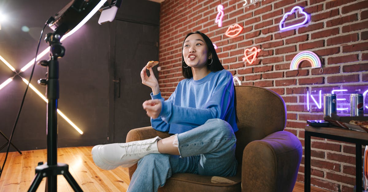 Young Asian woman streaming live indoors with neon lights, engaging audience through technology and creative content.